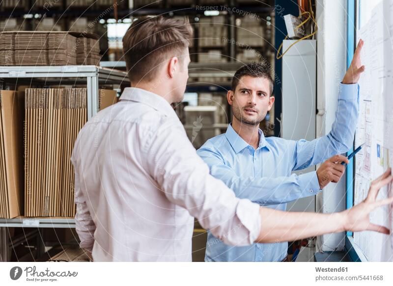 Zwei Geschäftsleute stehen in der Werkstatt und diskutieren über Pläne - ein  lizenzfreies Stock Foto von Photocase