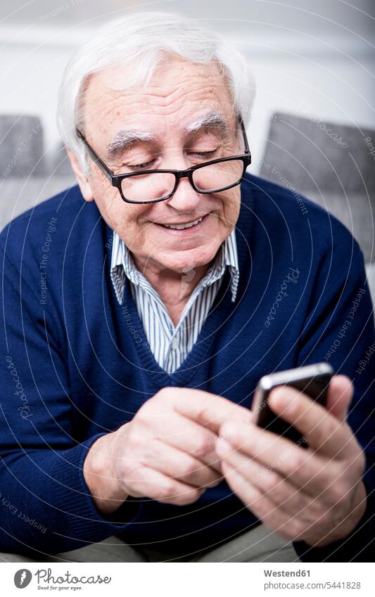 Älterer Mann benutzt Smartphone Handy Mobiltelefon Handies Handys Mobiltelefone lesen Lektüre sitzen sitzend sitzt Nachricht Mitteilung Botschaft SMS