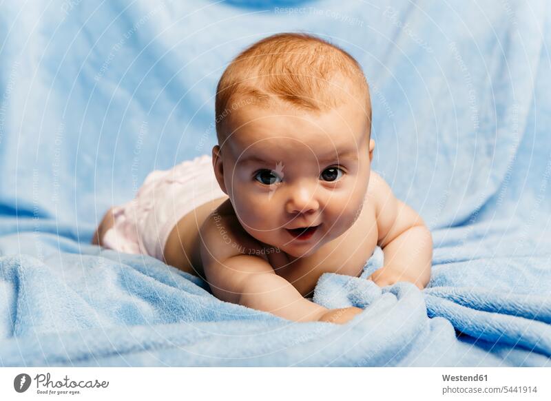 Bildnis eines lächelnden Mädchens auf einer hellblauen Decke liegend Portrait Porträts Portraits liegt Decken Baby Babies Babys Säuglinge Kind Kinder