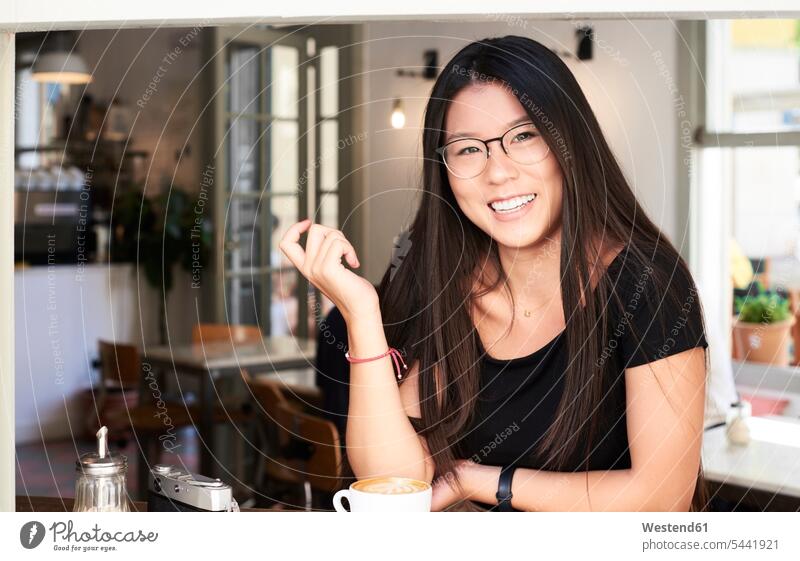 Asiatische junge Frau lächelt in einem Café in die Kamera lächeln Portrait Porträts Portraits Asiatin Asiatinnen asiatisch asiatische asiatisches asiatischer