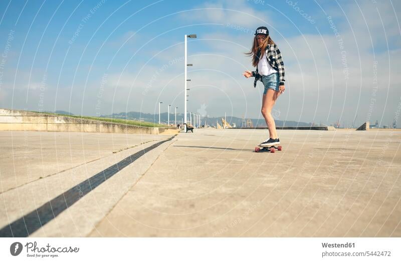 Junge Frau beim Longboarding an der Strandpromenade weiblich Frauen Skateboarderin Skateboardfahrerin Skaterin Skateboarderinnen Skaterinnen