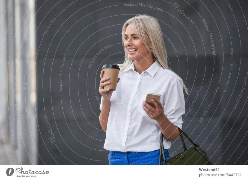 Glückliche Geschäftsfrau mit Kaffee zum Mitnehmen und Mobiltelefon im Freien Geschäftsfrauen Businesswomen Businessfrauen Businesswoman Frau weiblich Frauen