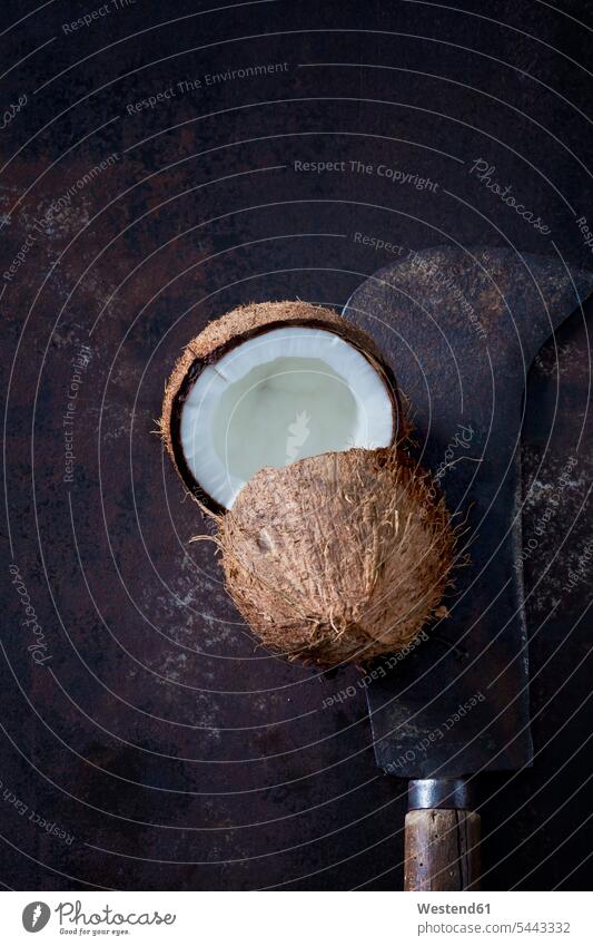 Geöffnete Kokosnuss und altes Hackbeil braun Hälfte halbe halbiert halber Haelfte tropisch hohl ausgehöhlt geöffnet offen brauner Hintergrund