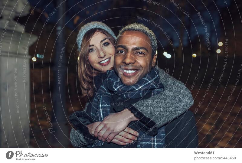 Porträt eines glücklichen jungen Paares vor dem Park Portrait Porträts Portraits Pärchen Partnerschaft Mensch Menschen Leute People Personen Winter winterlich