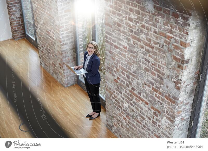 Glückliche Geschäftsfrau in moderner Büroetage mit Laptop Notebook Laptops Notebooks Geschäftsfrauen Businesswomen Businessfrauen Businesswoman Computer Rechner