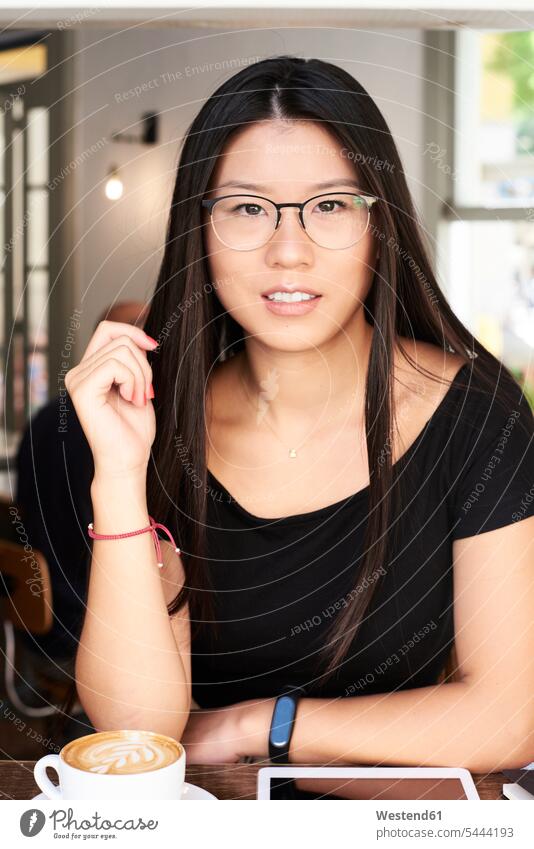 Porträt einer asiatischen jungen Frau, die in einem Café in die Kamera schaut Portrait Porträts Portraits lächeln weiblich Frauen Asiatin Asiatinnen asiatisches