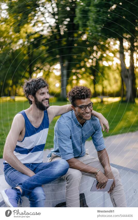 Zwei glückliche Freunde sitzen in einem Skatepark Skateboardpark Skateboard-Park Skateboard Park Skaterplatz Mann Männer männlich sitzend sitzt Glück