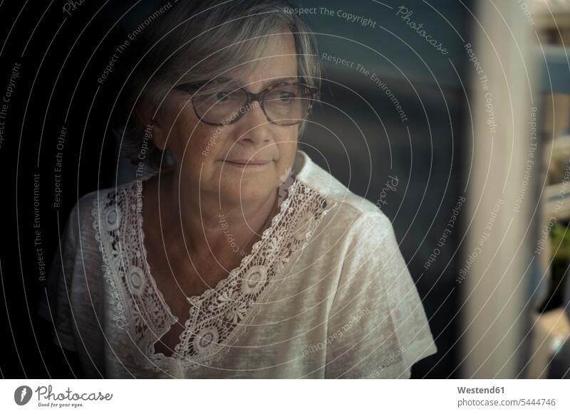 Porträt einer älteren Frau, die durch ein Fenster schaut Portrait Porträts Portraits Seniorin Seniorinnen alt Senioren weiblich Frauen Erwachsener erwachsen