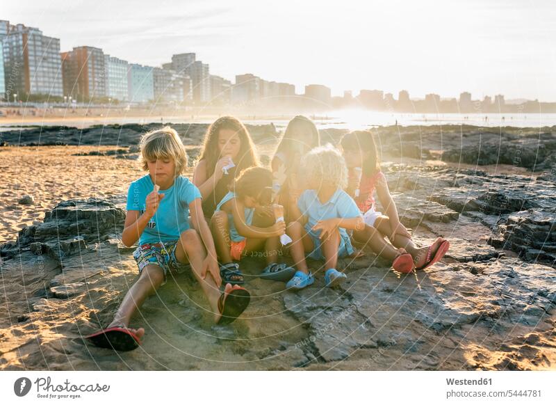 Eine Gruppe von sechs Kindern isst Eiscreme am Strand Speiseeis essen essend Kids Süßspeise Süsses Süßes süß Süßspeisen Essen Food Food and Drink Lebensmittel