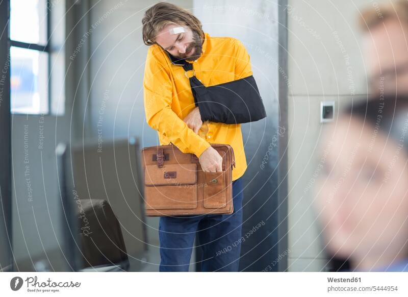 Verletzter Büroangestellter beim Anpassen seiner Tasche Office Büros Arbeitsplatz Arbeitsstätte Arbeitstelle Mann Männer männlich Erwachsener erwachsen Mensch