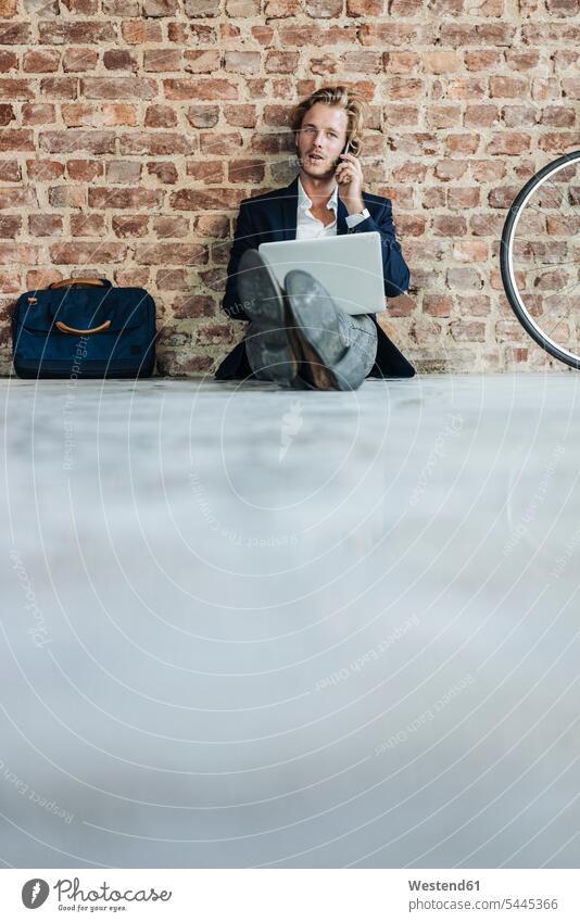 Geschäftsmann sitzt auf dem Boden und benutzt Laptop und Mobiltelefon Notebook Laptops Notebooks Mann Männer männlich Umzug umziehen sitzen sitzend telefonieren