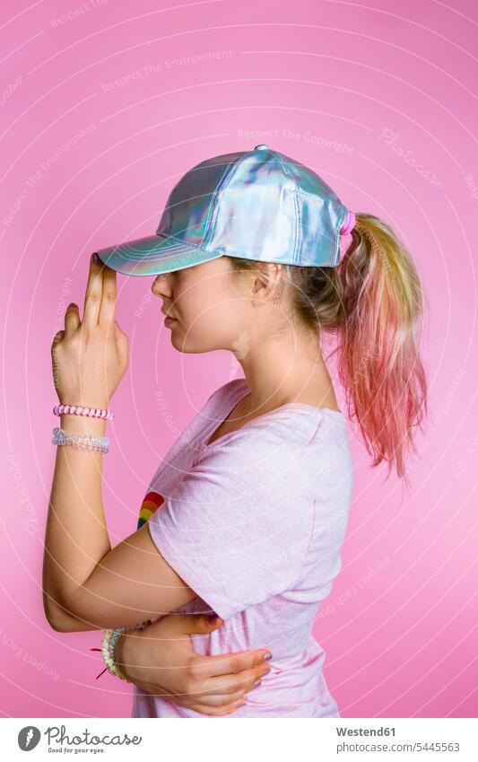 Stilvolle junge Frau mit gefärbten Haaren mit Basecap vor rosa Hintergrund weiblich Frauen Erwachsener erwachsen Mensch Menschen Leute People Personen Käppi