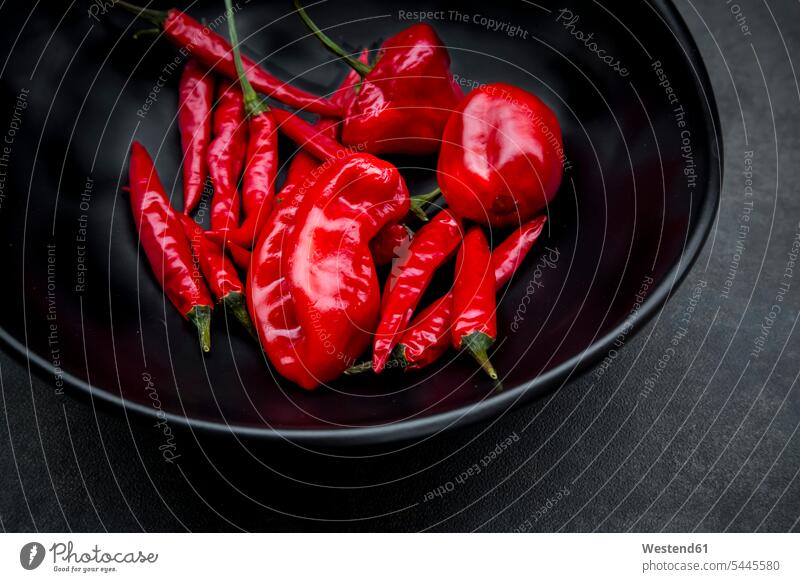 Schwarze Schale mit verschiedenen roten Chili-Schoten glänzend glaenzend Glanz roter rotes Peperoni Peperonis scharfe Paprikas Chilis scharfer Paprika Schüssel