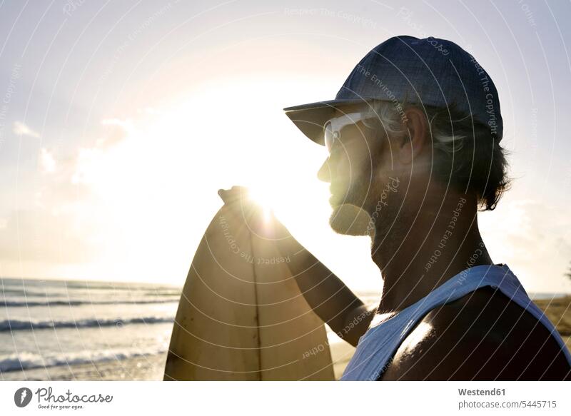 Mann mit Surfbrett beim Sonnenuntergang am Strand Surfbretter surfboard surfboards Männer männlich Surfer Wellenreiter Surfen Surfing Wellenreiten Wassersport