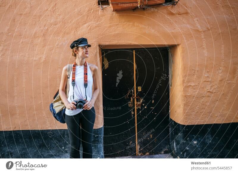 Junge Frau mit Kamera vor altem Haus stehend steht weiblich Frauen Touristin Fotoapparat Fotokamera Erwachsener erwachsen Mensch Menschen Leute People Personen
