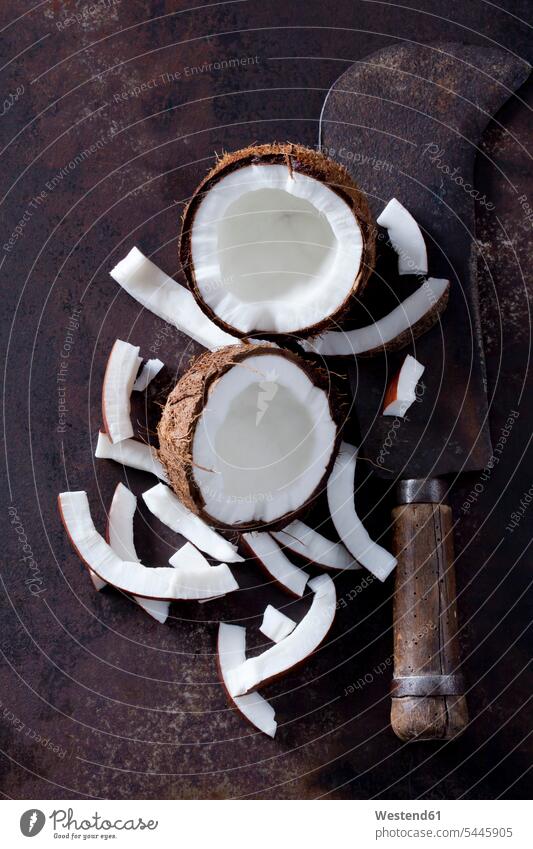 Geöffnete Kokosnuss, Kokontu-Stücke und ein altes Hackbeil braun geschält tropisch aufgeschnitten Scheibe angeschnitten Scheiben Gruppierung Anordnung Ordnung