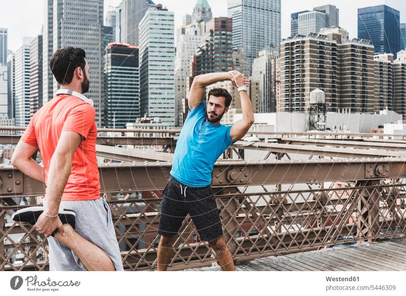USA, New York City, zwei Athleten strecken sich auf der Brooklyn Brige Joggen Jogging Freunde dehnen Mann Männer männlich Brücke Bruecken Brücken Fitness fit