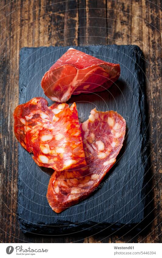Scheiben spanische Salami und Scheibe italienischer Schinken auf Schiefer rot rote roter rotes hölzern Stück Spezialität Italienische Küche luftgetrocknet