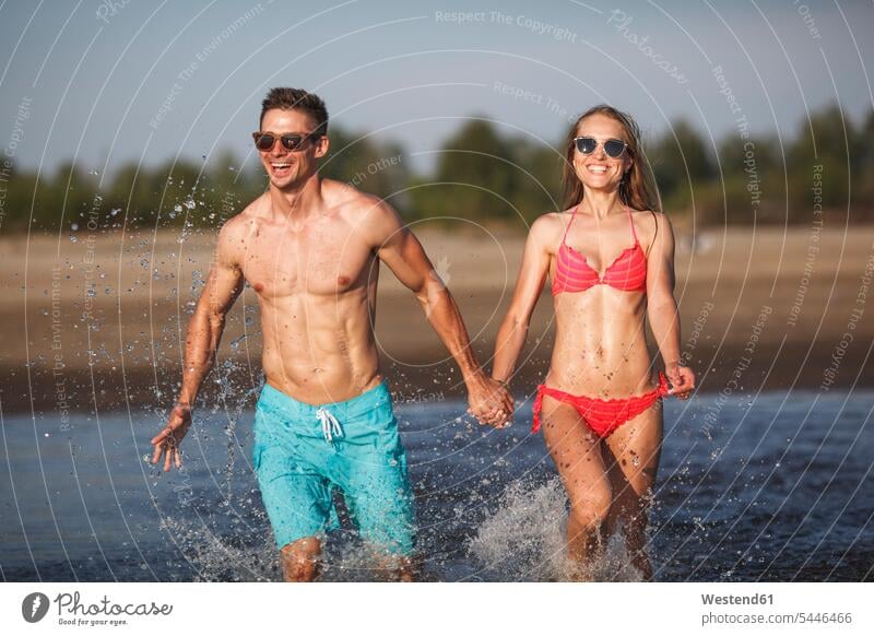 Glückliches, im Wasser plantschendes Paar lachen See Seen Spaß Spass Späße spassig Spässe spaßig Pärchen Paare Partnerschaft positiv Emotion Gefühl Empfindung