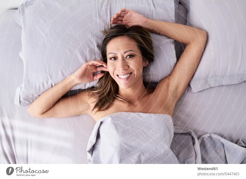 Porträt einer lächelnden Frau ohne Pyjama im Bett liegend Betten Portrait Porträts Portraits liegt weiblich Frauen Erwachsener erwachsen Mensch Menschen Leute