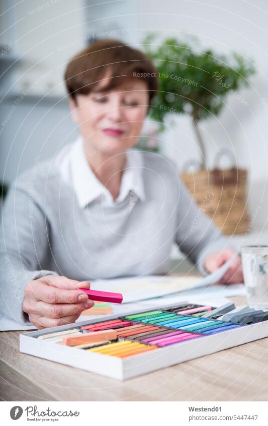 Ältere Frau zeichnet Bild mit Buntstiften weiblich Frauen aussuchen auswählen Malkreide malen zeichnen Zeichnung Kreide sitzen sitzend sitzt Seniorin älter