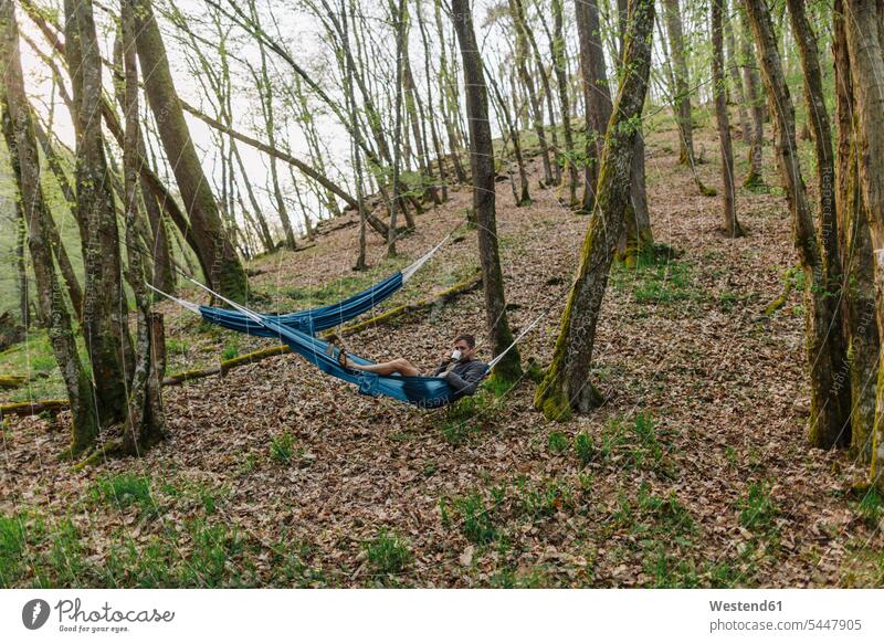 Deutschland, Rheinland-Pfalz, Vulkaneifel, junger Mann in Hängematte im Wald liegend Männer männlich Auszeit Alles hinter sich lassen abschalten entspannen