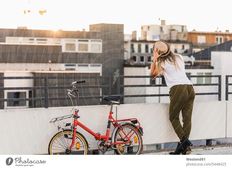 Junge Frau mit Fahrrad, das gegen ein Geländer lehnt Stadt staedtisch städtisch weiblich Frauen Bikes Fahrräder Räder Rad anlehnen angelehnt lehnend