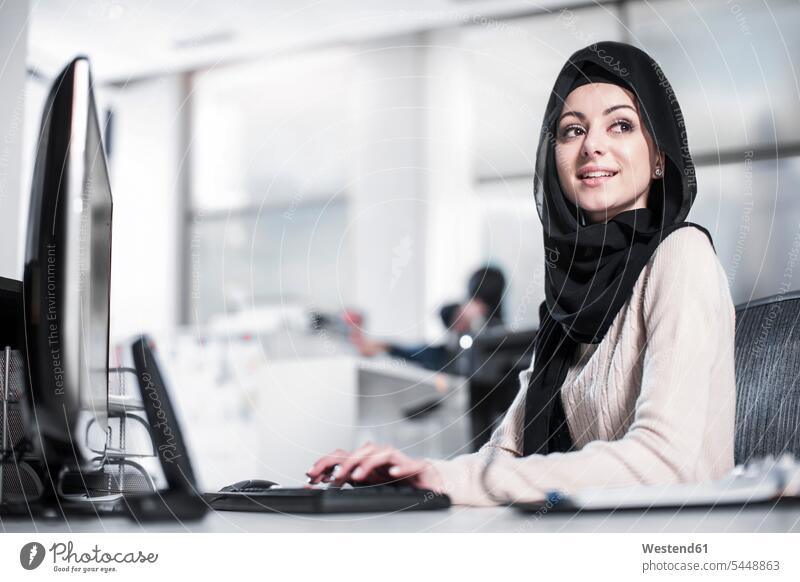 Junge Frau mit Hijab bei der Arbeit am Schreibtisch im Büro lächeln weiblich Frauen Portrait Porträts Portraits Office Büros arbeiten Kopftuch Kopftücher