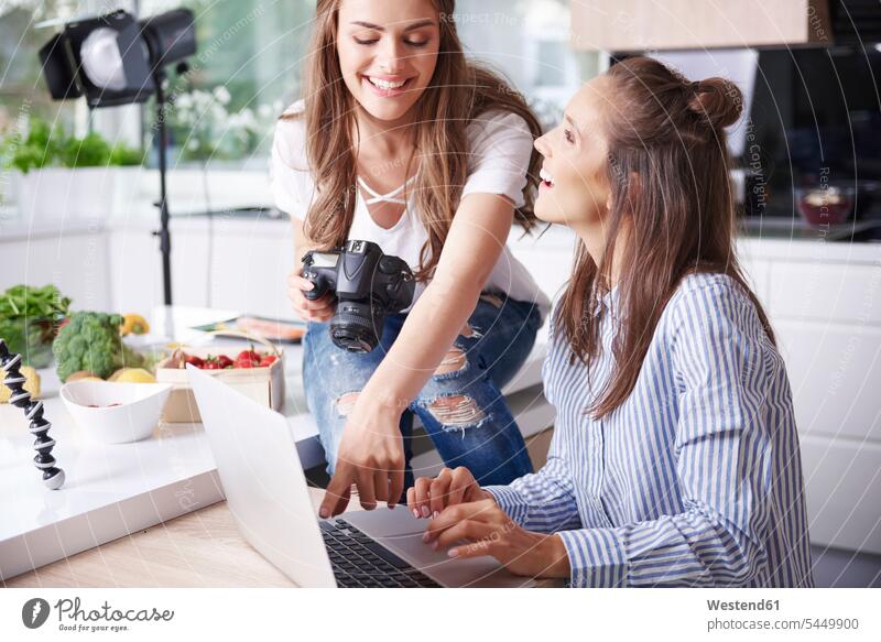 Glückliche Blogger benutzen Laptop in der Küche Fotokamera Kamera Kameras Rechner Laptops Notebook Notebooks Leute Menschen People Person Personen erwachsen