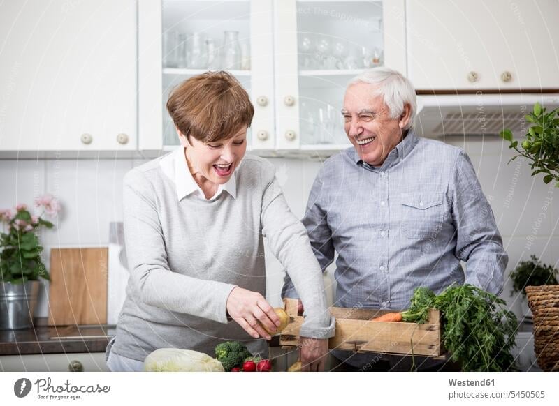 Älteres Ehepaar steht in der Küche und packt frisches Gemüse aus Europäer Kaukasier Europäisch kaukasisch Freude freuen glücklich Glück glücklich sein