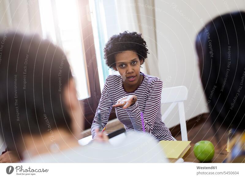 Gruppe von Studentinnen diskutiert zu Hause am Tisch Tische Teamwork Teamarbeit Zusammenarbeit Hochschülerin Hochschülerinnen Hochschuelerinnen sprechen reden