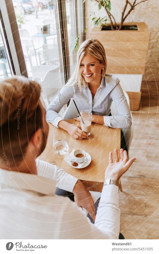 Glückliche junge Frau schaut den Mann in einem Café an Paar Pärchen Paare Partnerschaft Cafe Kaffeehaus Bistro Cafes Cafés Kaffeehäuser sprechen reden lachen