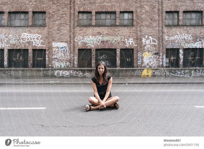 Frau sitzt auf der Straße Strassen Straßen weiblich Frauen sitzen sitzend Erwachsener erwachsen Mensch Menschen Leute People Personen Außenaufnahme draußen