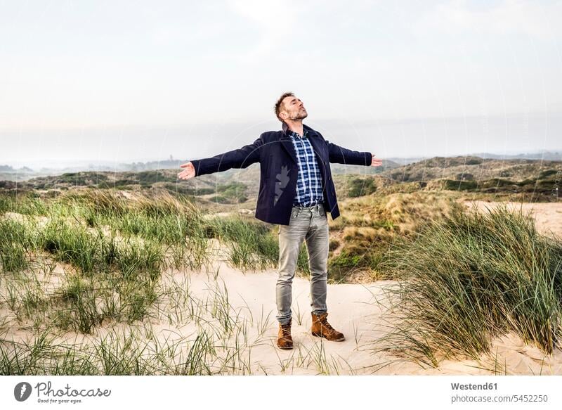 Mann steht mit ausgestreckten Armen in den Dünen stehen stehend Strand Beach Straende Strände Beaches Männer männlich Sanddüne Sanddünen Erwachsener erwachsen