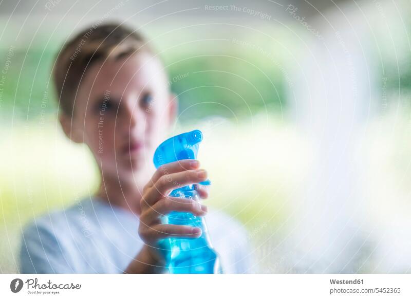 Junge sprüht mit Fensterreiniger Buben Knabe Jungen Knaben männlich Putzmittel Zuhause zu Hause daheim säubern saeubern Sprayflasche Sprühflasche Sprayflaschen