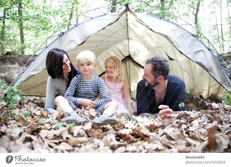Glückliche Familie mit Zelt im Wald Forst Wälder Zelte Familien lächeln Mensch Menschen Leute People Personen Quality Time Tochter Töchter glücklich