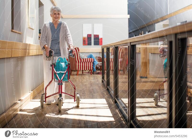 Ältere Frau im Altenheim schiebt Rollator gehen gehend geht schieben anschieben Altersheim Seniorenheim Rollgestell Gehhilfe Rollwagen Seniorin älter