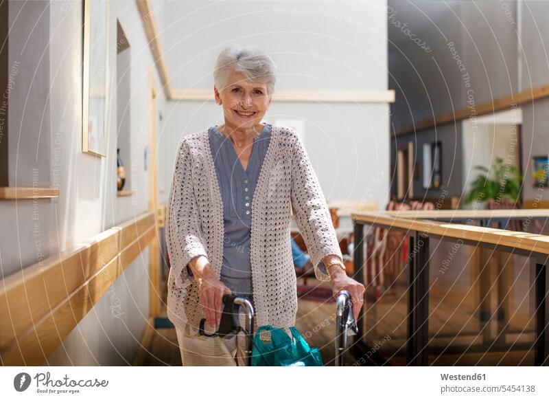 Ältere Frau im Altenheim schiebt Rollator gehen gehend geht schieben anschieben Altersheim Seniorenheim Rollgestell Gehhilfe Rollwagen Seniorin älter
