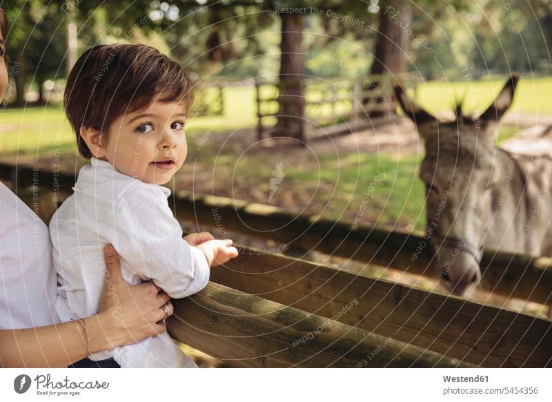 Porträt eines Kleinkindes, das von seiner Mutter in einem Wildpark gehalten wird Wildparks Portrait Porträts Portraits Junge Buben Knabe Jungen Knaben männlich