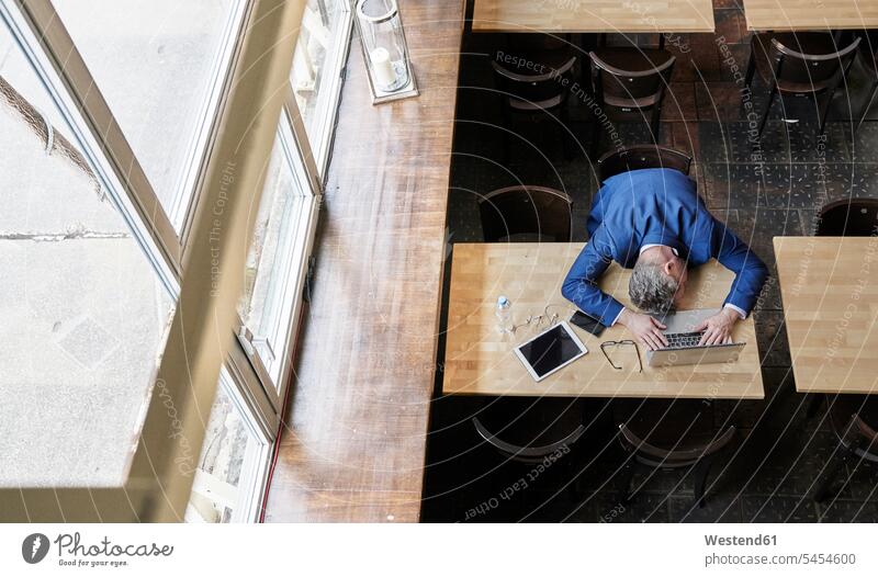 Erschöpfter reifer Geschäftsmann im Cafe mit Laptop, Tablet und Handy Erschöpfung erschöpft Businessmann Businessmänner Geschäftsmänner Notebook Laptops