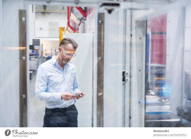 Mann mit Schutzbrille in Fabrikhalle Männer männlich Geschäftsmann Businessmann Businessmänner Geschäftsmänner Fabriken Erwachsener erwachsen Mensch Menschen