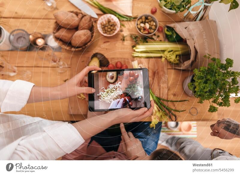 Freunde kochen zusammen und fotografieren zubereitetes Gemüse mit Tablette, Draufsicht Tablet Computer Tablet-PC Tablet PC iPad Tablet-Computer Rechner halten