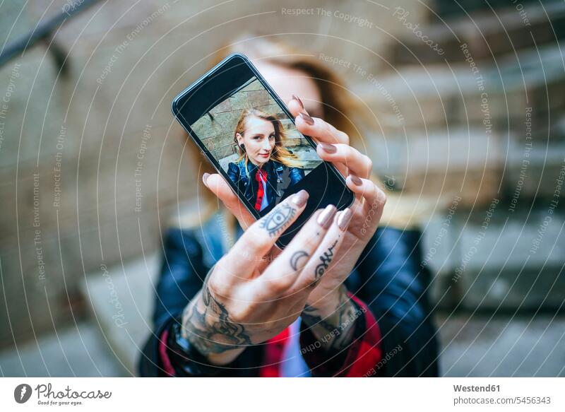 Hände einer tätowierten Frau, die ein Selfie mit einem Smartphone macht, Nahaufnahme Selfies iPhone Smartphones Tattoo Tätowierungen Tatoos Taetowierung Tattoos