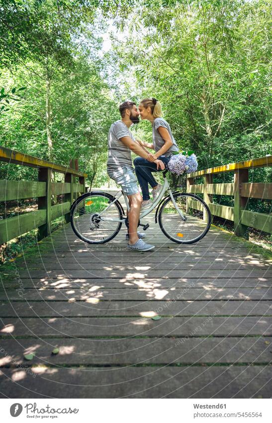 Paar mit Fahrrad vor dem Kuss auf einem Holzsteg auf dem Land Pärchen Paare Partnerschaft Weg Wege Pfad Bikes Fahrräder Räder Rad küssen Küsse ländlich