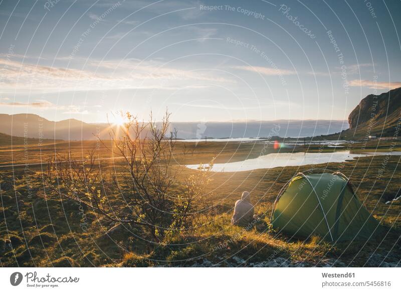 Norwegen, Lofoten, Moskenesoy, Junger Mann beim Zelten in Hovdanvika zelten Camping Campen nachdenken überlegen sitzen sitzend sitzt Abend abends