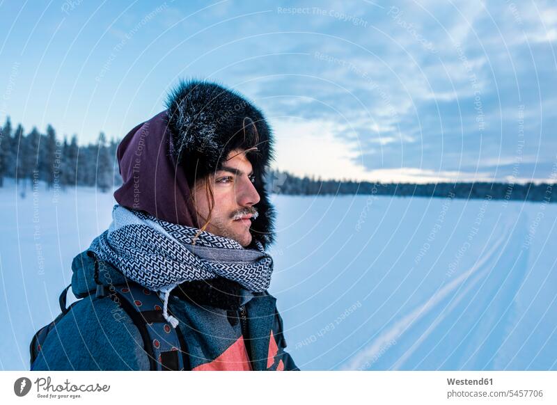 Porträt eines Mannes in Winterlandschaft mit gefrorenem Schnurrbart, Ounasjaervi, Enontekioe, Finnland Touristen Mützen Schals Daemmerung Jahreszeiten
