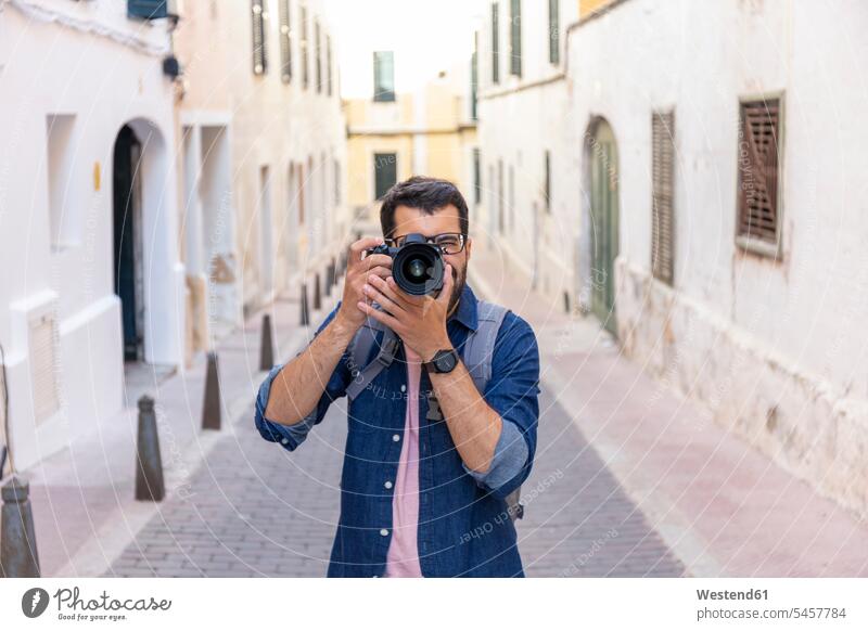 Mann fotografiert mit der Kamera in der Stadt, Mao, Menorca, Spanien Touristen Rucksäcke Brillen Fotokamera Kameras stehend steht erforschen Erforschung
