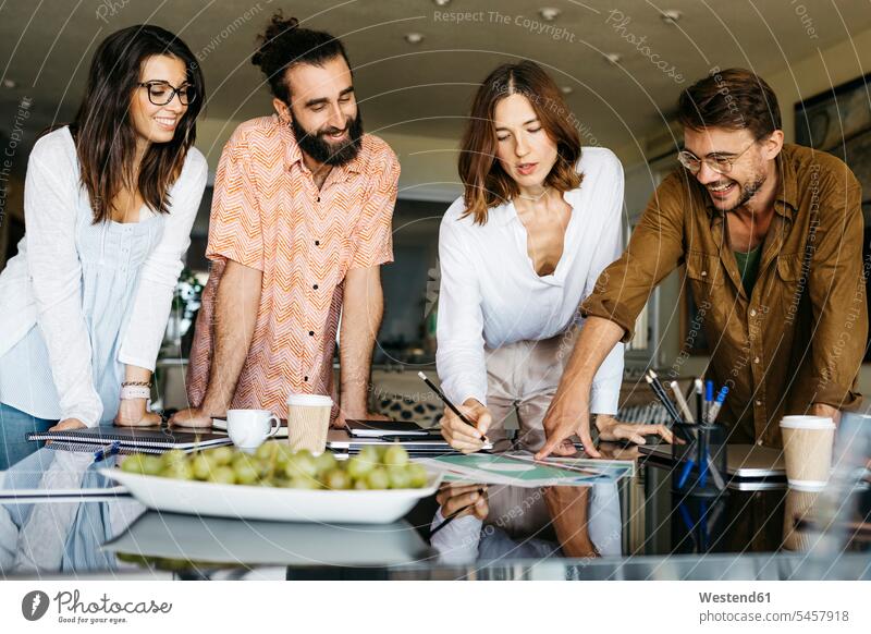 Glückliche Freunde arbeiten zu Hause am Tisch zusammen Leute Menschen People Person Personen Europäisch Kaukasier kaukasisch Südeuropäisch Gruppe von Menschen