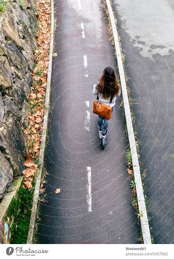 Junge Frau fährt Elektroroller auf der Straße fahren Roller Tretroller aktiv Strassen Straßen E-Scooter Aktivität Aktivitaet Verkehrswesen Transportwesen