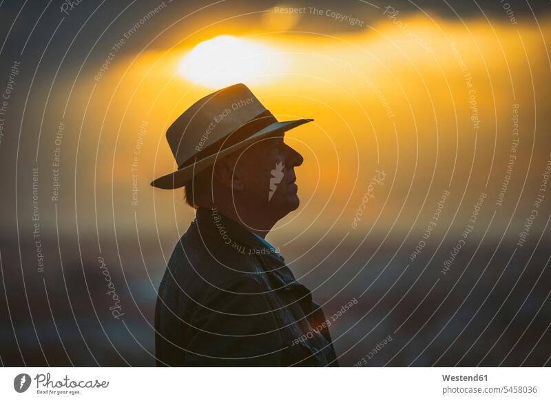 Älterer Mann mit Hut gegen den Himmel bei Sonnenuntergang Farbaufnahme Farbe Farbfoto Farbphoto Außenaufnahme außen draußen im Freien Sonnenuntergänge Stimmung